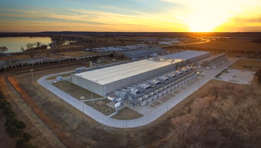 Aerial view of a data centre campus at sunset, its cooling plant, roads and open land around it