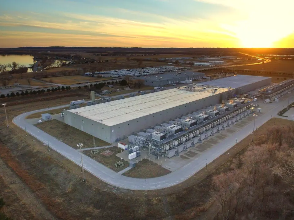 Aerial view of a data centre campus at sunset, its cooling plant, roads and open land around it