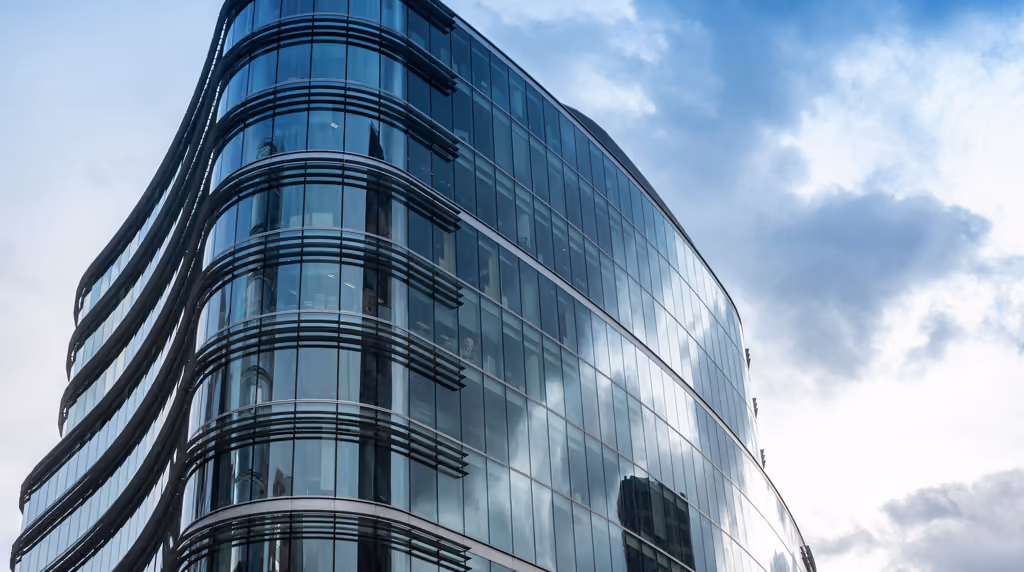 Curved glass office building in London reflecting the clouds