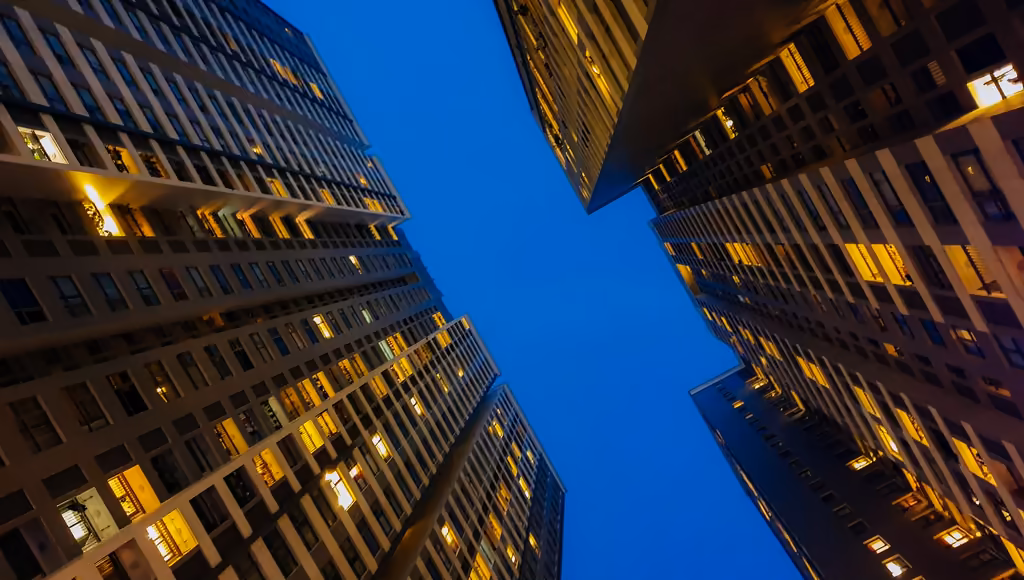 Two lit towers seen from below, closing in on a strip of blue sky