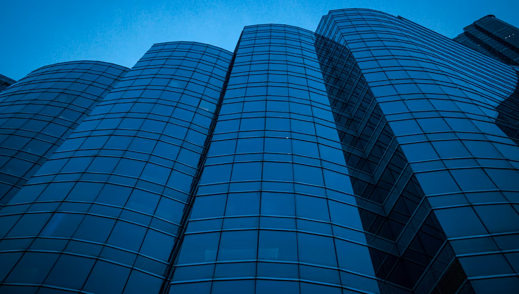 Folded glass facade of an office building at blue hour, seen from below