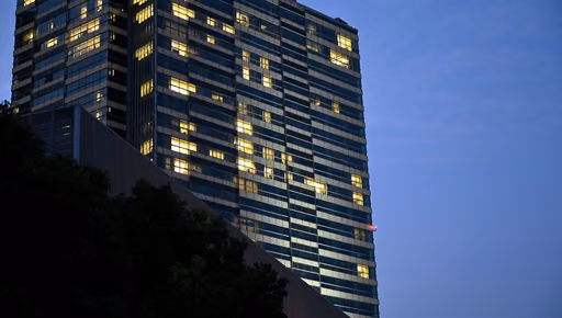 Office tower with its lit floors against a dusk sky