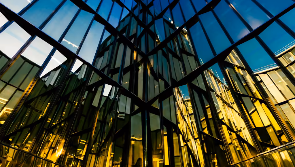 Glass facade seen from below at blue hour, the lit interior showing through