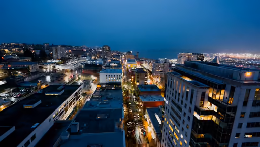 City blocks and rooftops seen from above at blue hour, windows lit